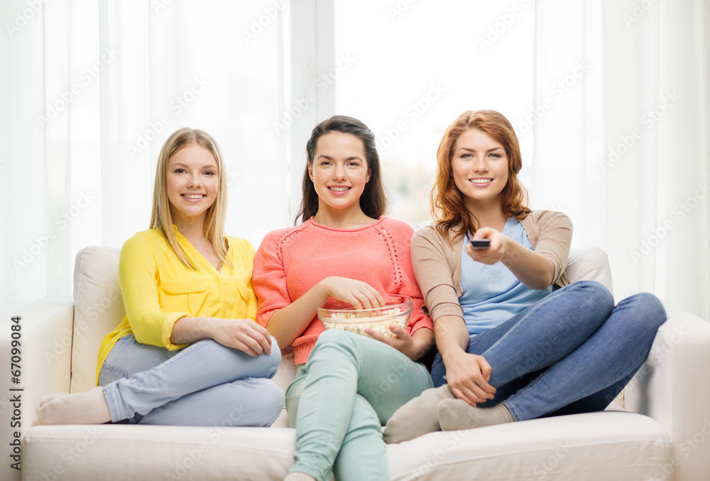 three smiling teenage girl watching tv at home three smiling teenage girl watching tv at home