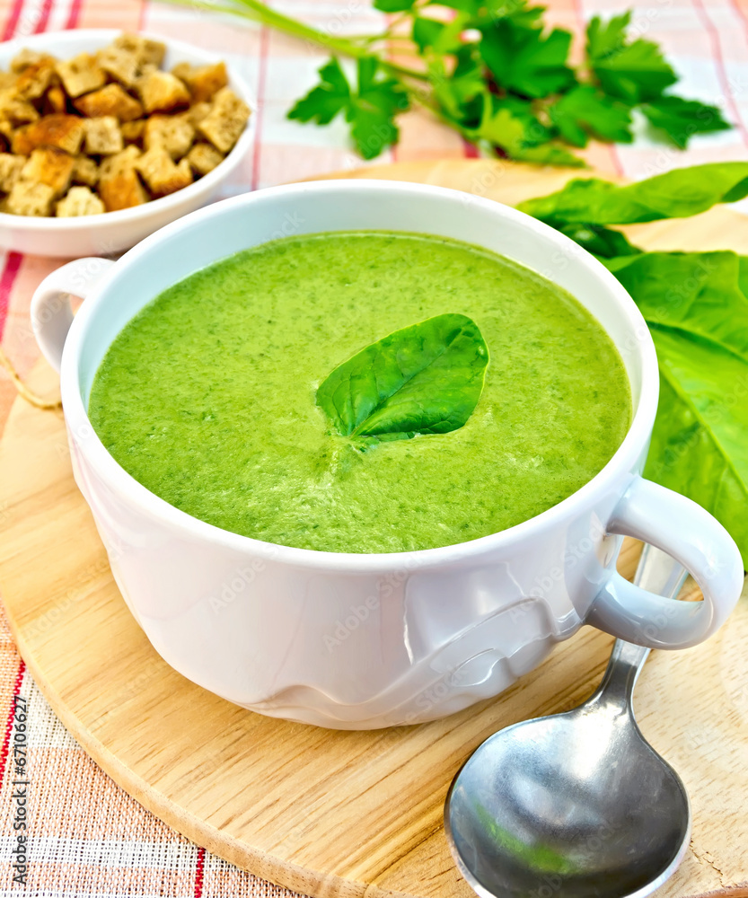 Soup puree with spinach leaves and spoon on fabric Soup puree with spinach leaves and spoon on fabric