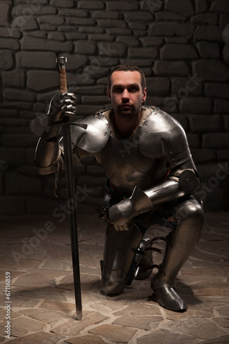 Slika na platnu Medieval knight kneeling with sword