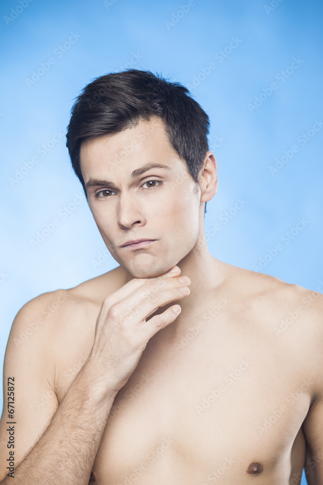 Handsome shirtless man in front of mirror looking at his chin Handsome shirtless man in front of mirror looking at his chin