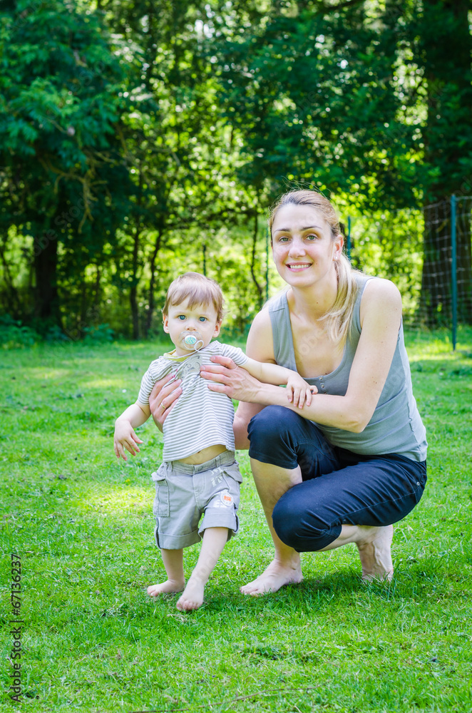 Fototapeta premium Little cute baby boy walking with young mother in park