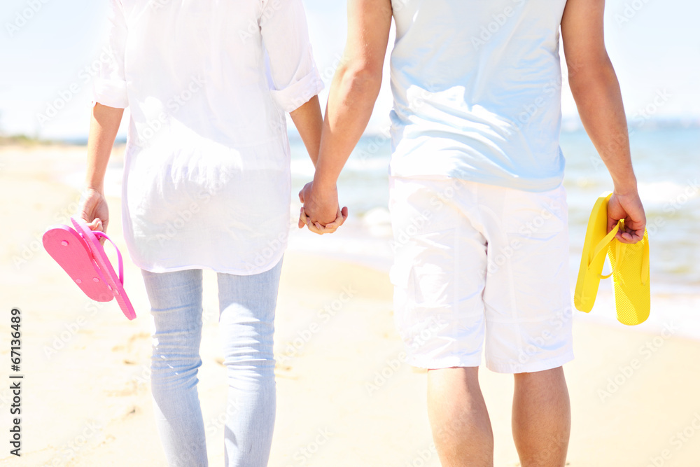 Couple walking at the beach and carrying flip flops Couple walking at the beach and carrying flip flops