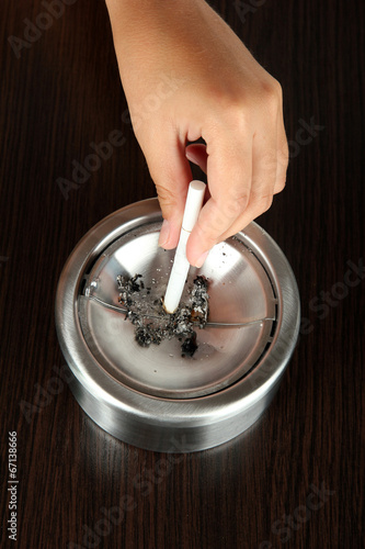 Metal ashtray and cigarette on wooden table