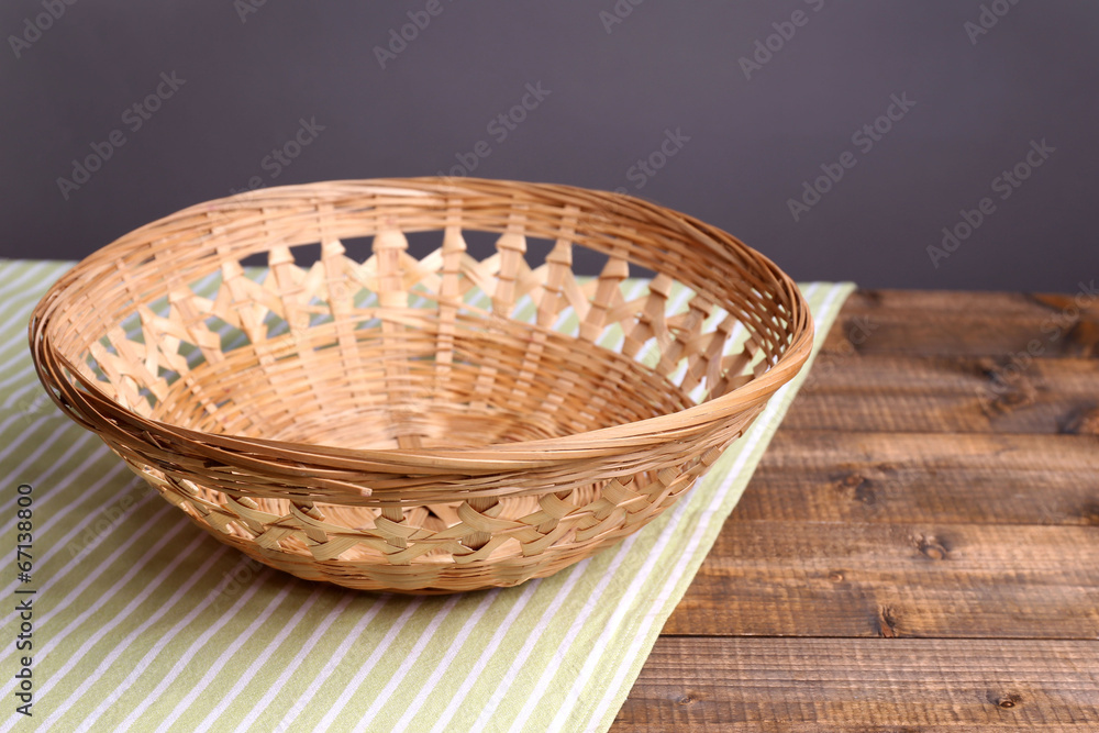 Empty wicker basket on wooden table, on dark background Empty wicker basket on wooden table, on dark background