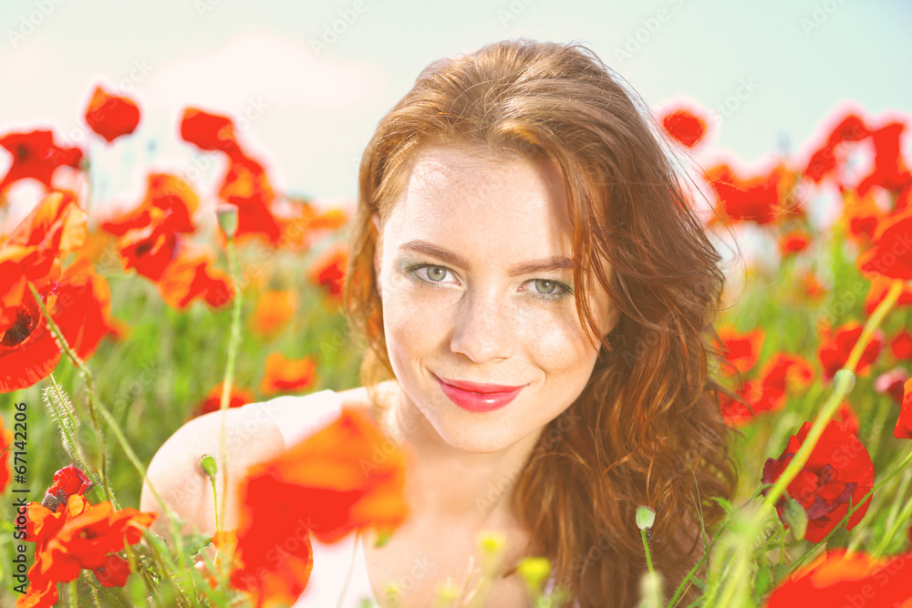Naklejka premium Beautiful young woman in poppy field