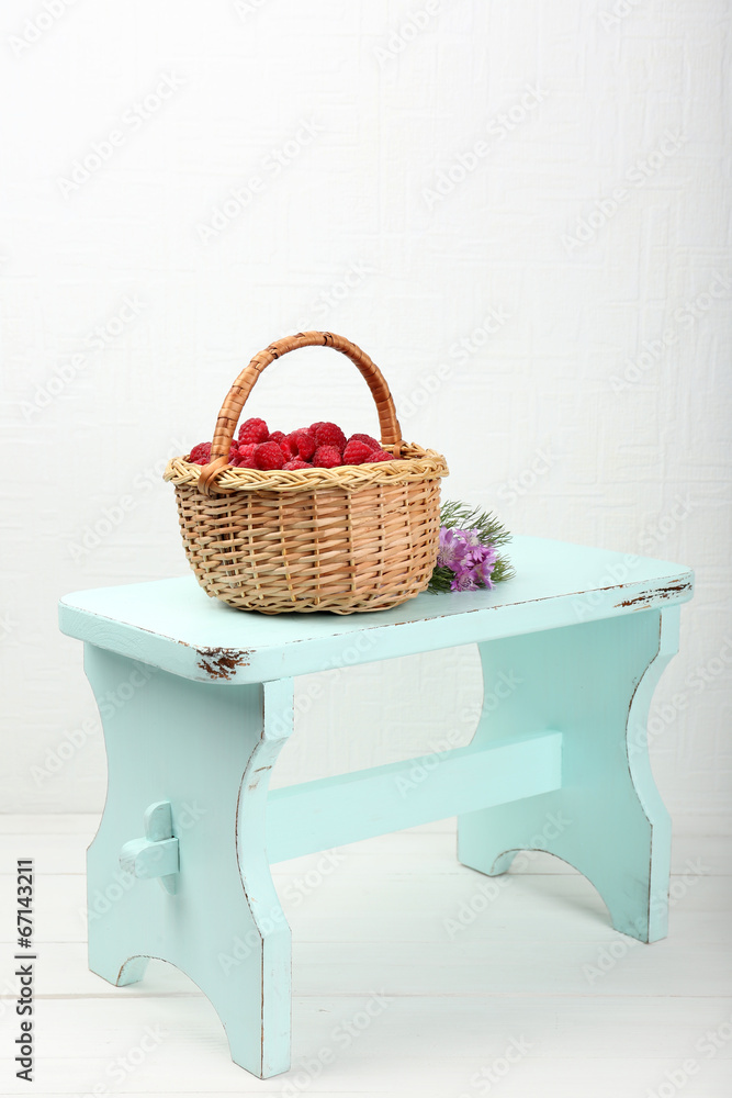 Fresh raspberries in basket on white wall background