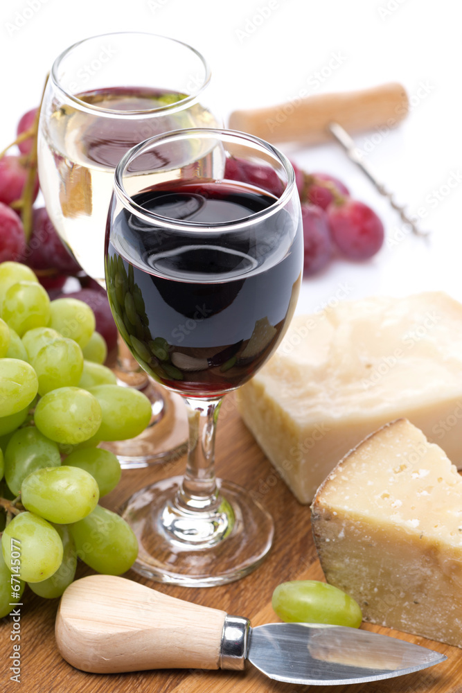 grapes, hard cheese and two glasses of wine on wooden board