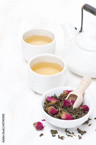 green tea with rosebuds in a bowl  cups and teapot  vertical