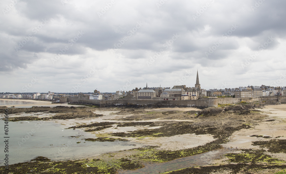 view of the shore from saint malo on a cloudy day - obrazy, fototapety, plakaty 