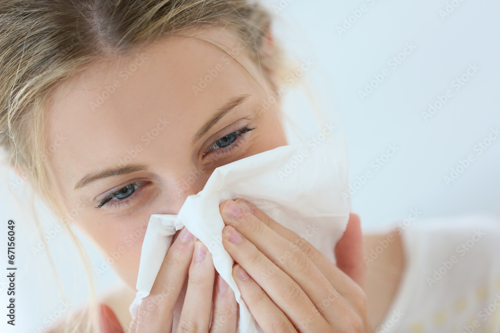 Young woman with cold blowing her runny nose Young woman with cold blowing her runny nose