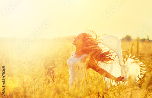 Teenage model girl in white dress running on the spring field