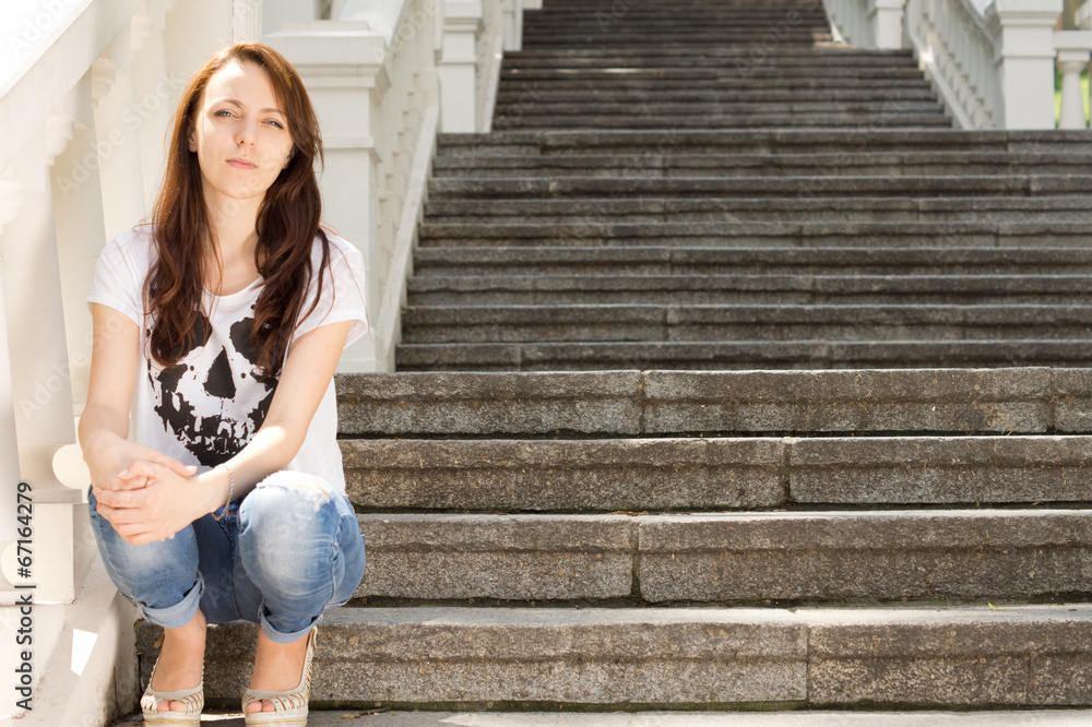 Lonely young woman sitting on a staircase Lonely young woman sitting on a staircase