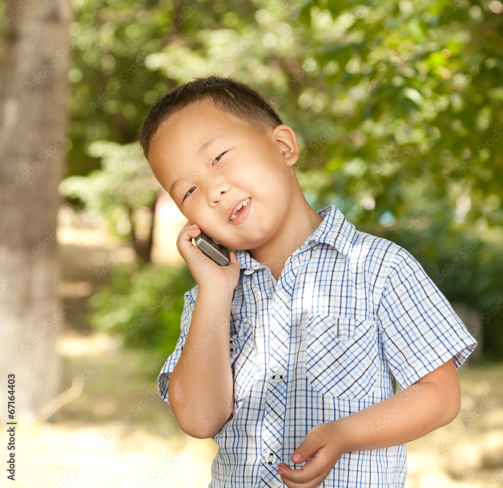 funny asian boy with a mobile phone in a park