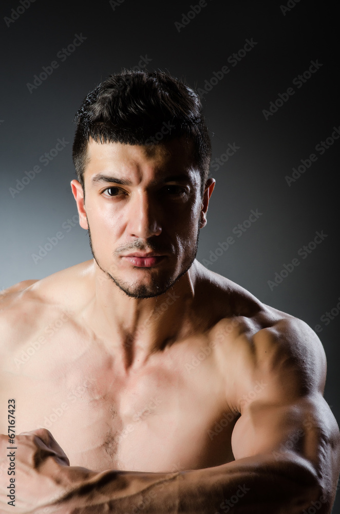 Fototapeta premium Muscular man posing in dark studio