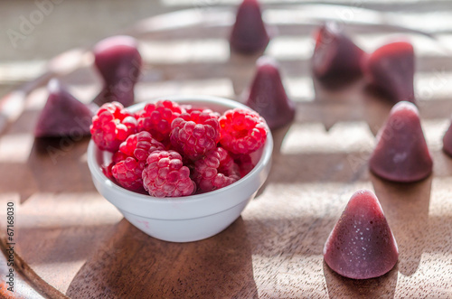 Cuberdons with fresh raspberries on the wooden board photo