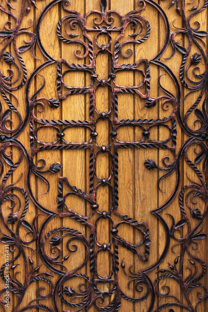 forged wooden door with a cross in the church