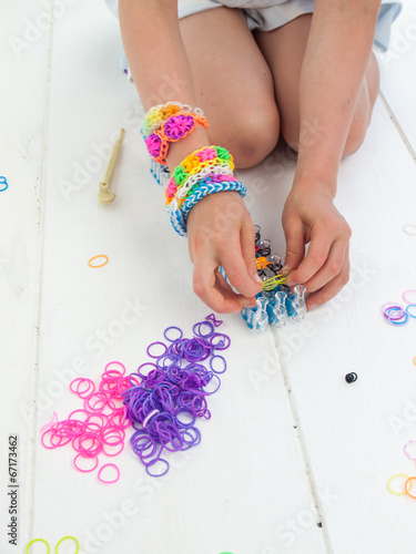 kneeling childs hands making a multicoloured elastic band bracel photo