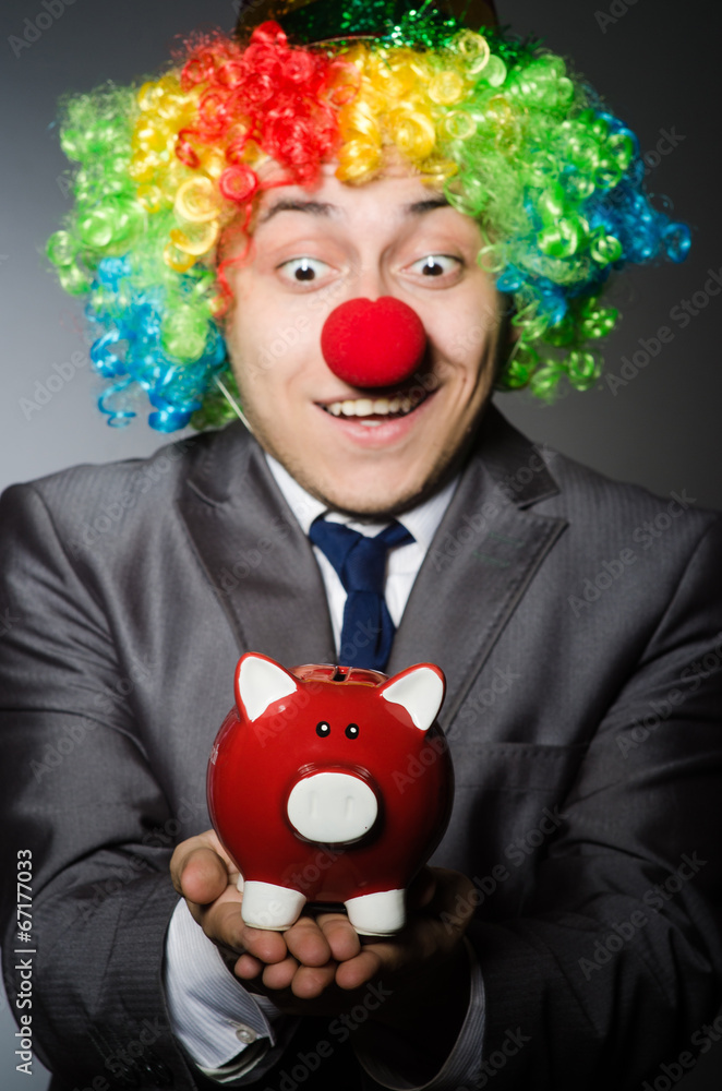 Clown with piggybank in funny concept Clown with piggybank in funny concept