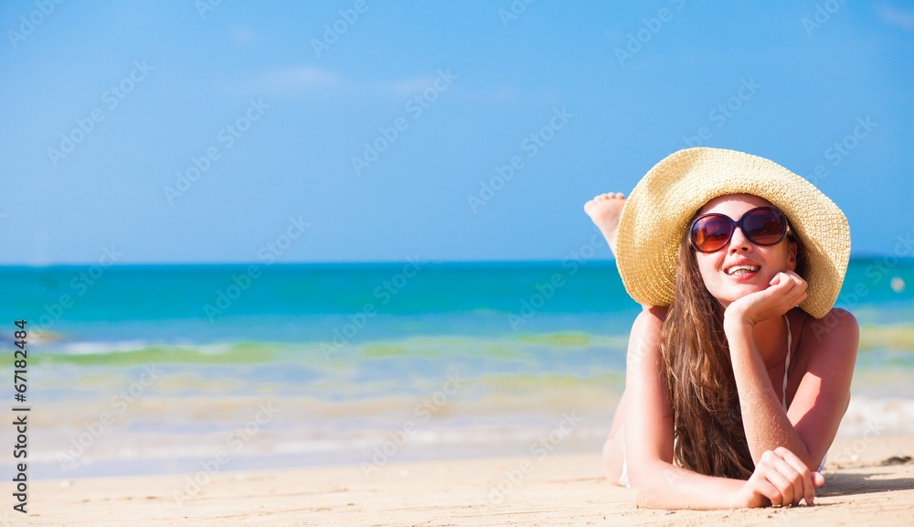 long haired woman in bikini and straw hat at tropical beach