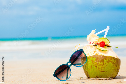 picture of fresh coconut cocktail and blue sunglasses on