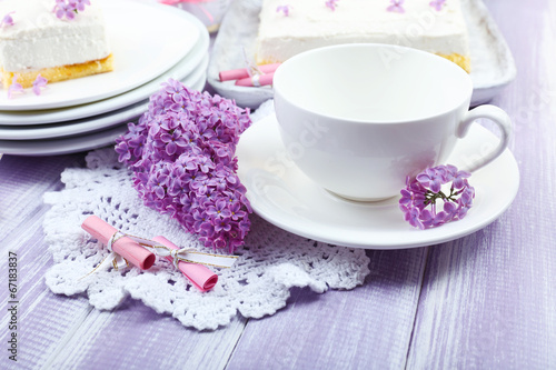 White cup with delicious dessert and lilac flowers