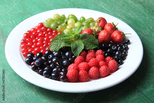 Forest berries on plate  on color wooden background