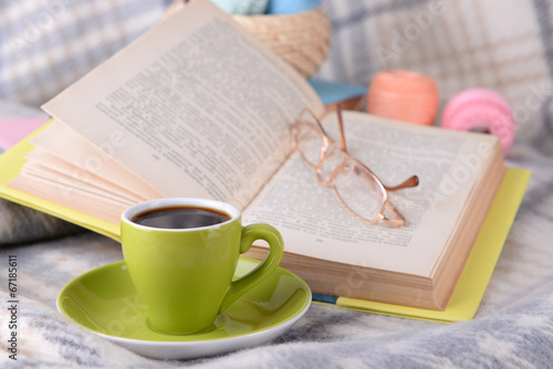 Cup of coffee and yarn for knitting on plaid with books