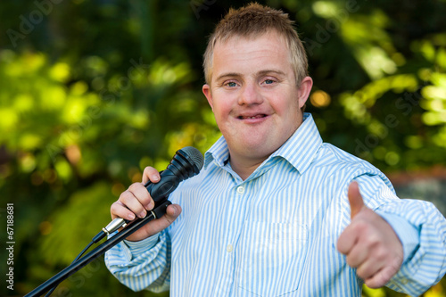 Handicapped boy with microphone doing thumbs up. photo