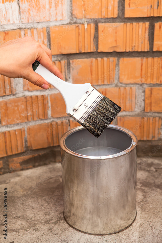 CLear paint brush in human hand over can with grey color CLear paint brush in human hand over can with grey color