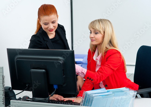 two woman colegues working on computer in office photo