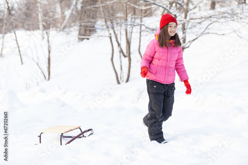 young girl walking on snow with sledges.