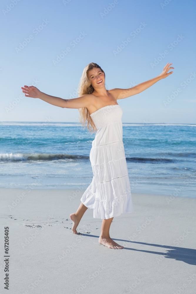 Beautiful blonde in white sundress on the beach smiling at camer Beautiful blonde in white sundress on the beach smiling at camer