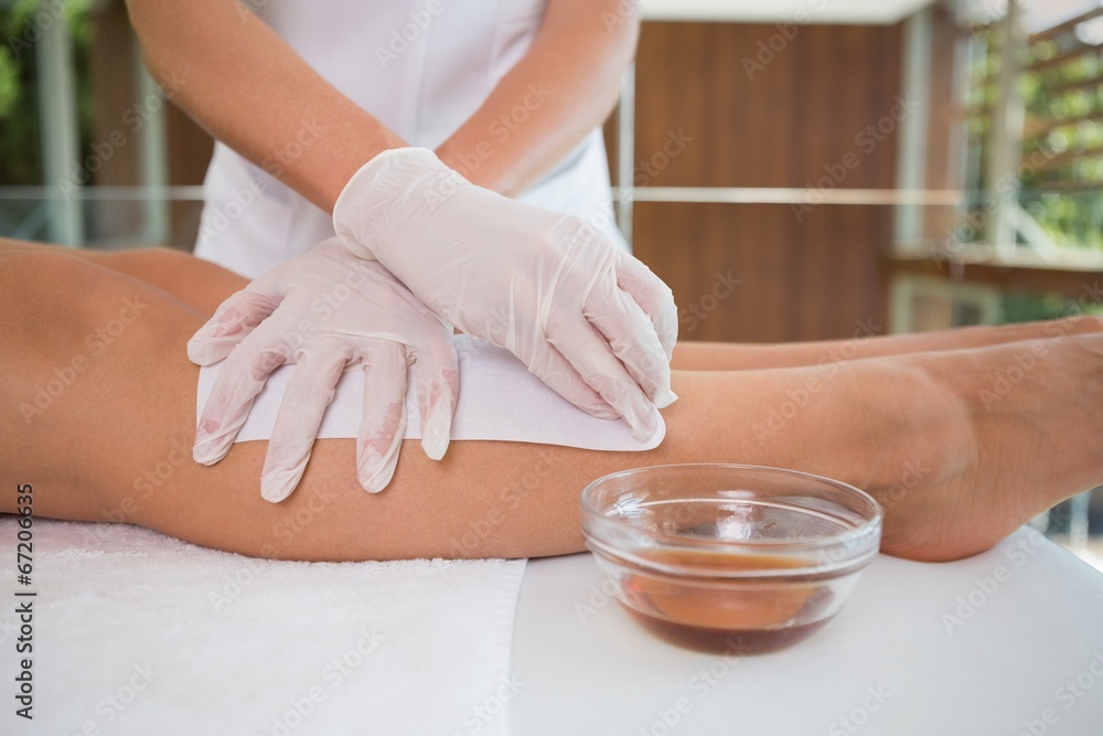 Woman getting her legs waxed by beauty therapist Woman getting her legs waxed by beauty therapist
