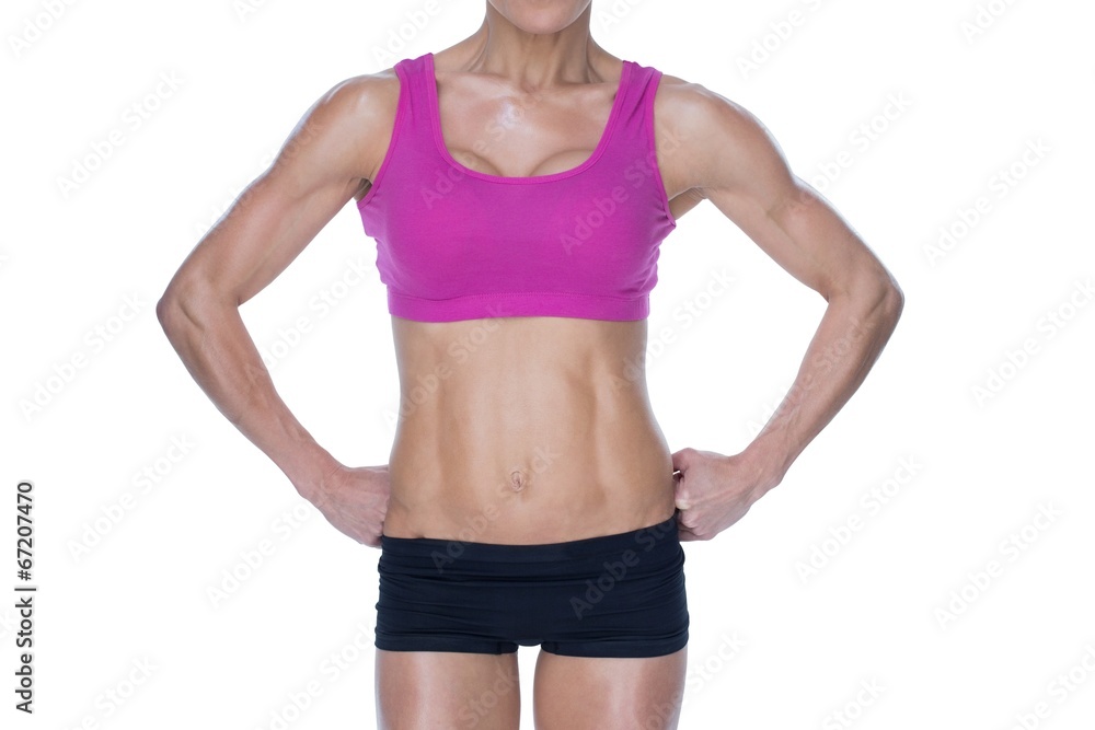 Female bodybuilder posing in pink sports bra and shorts mid sect Female bodybuilder posing in pink sports bra and shorts mid sect
