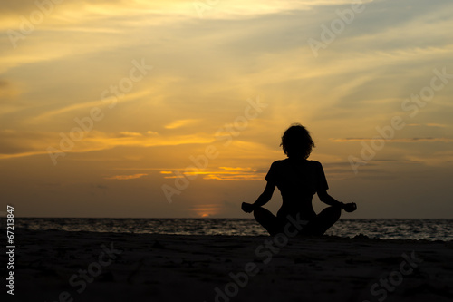 Fototapeta Naklejka Na Ścianę i Meble -  Yoga woman sitting on sea coast at sunset.