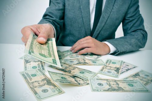 man in suit giving dollar bills