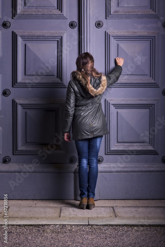 Young Woman Knocking on Old Wooden Door. Winter