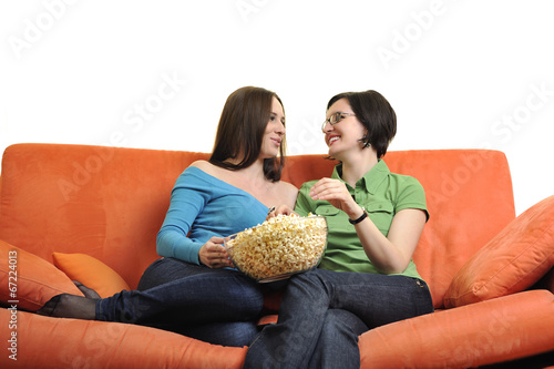 female friends eating popcorn and watching tv at home