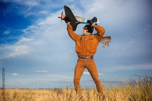 Obraz na plátne Guy in vintage clothes pilot with an airplane model outdoors