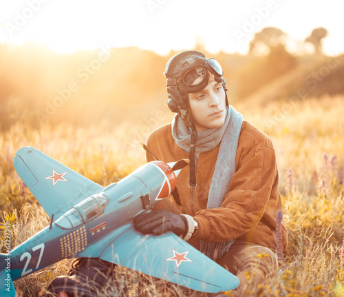 Tela Guy in vintage clothes pilot with an airplane model outdoors