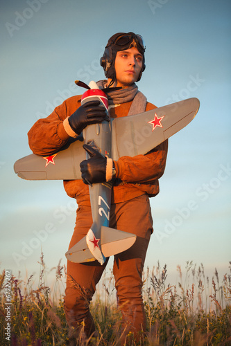 Fototapeta Guy in vintage clothes pilot with an airplane model outdoors
