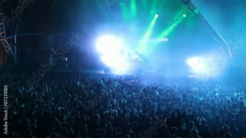 Huge crowd dancing at a DJ show, with great lightning effects photo