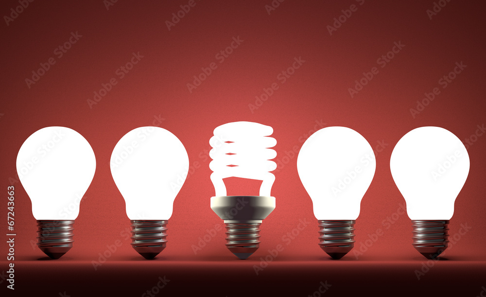 Glowing spiral light bulb in row of tungsten ones on red Glowing spiral light bulb in row of tungsten ones on red