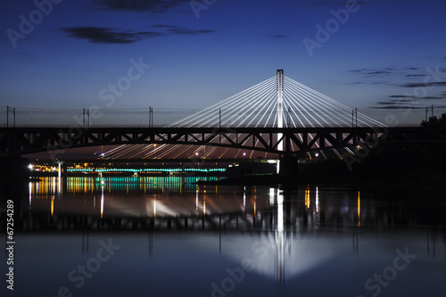 Highlighted bridge at night and reflected in the water #67254289