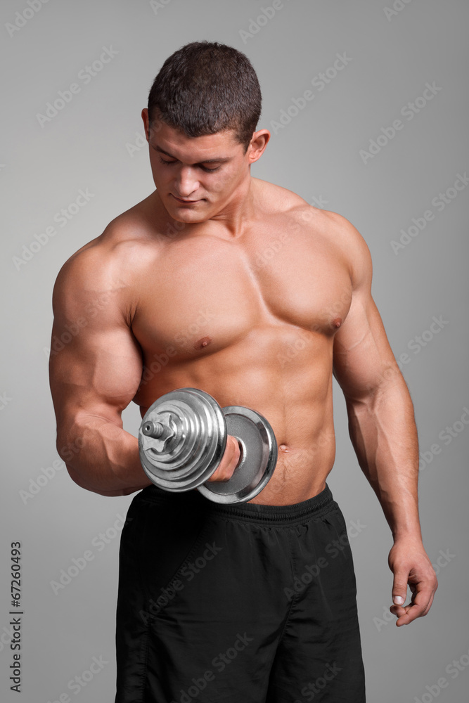 muscular man working out with dumbbells on gray background