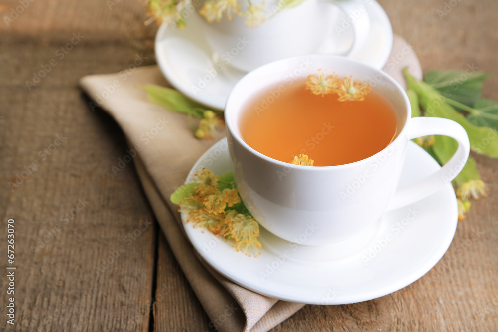 Tasty herbal tea with linden flowers on wooden table Tasty herbal tea with linden flowers on wooden table