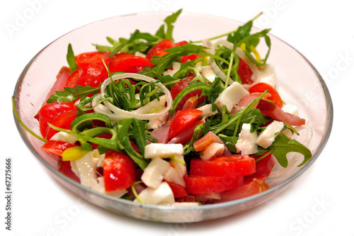 Mediterranean salad with feta cheese, tomato and rucola served in a bowl, isolated on white background