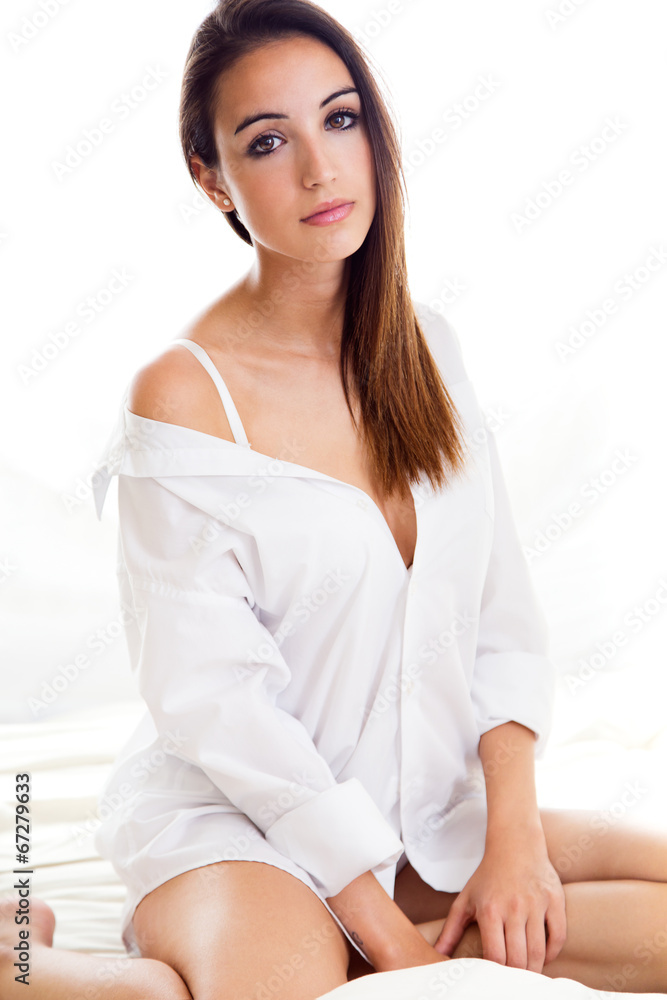 Young beautiful woman sitting on the bed. Isolated on white. Young beautiful woman sitting on the bed. Isolated on white.