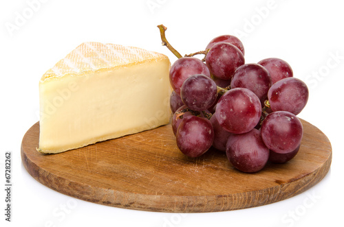 Cheese with grapes on a wooden board