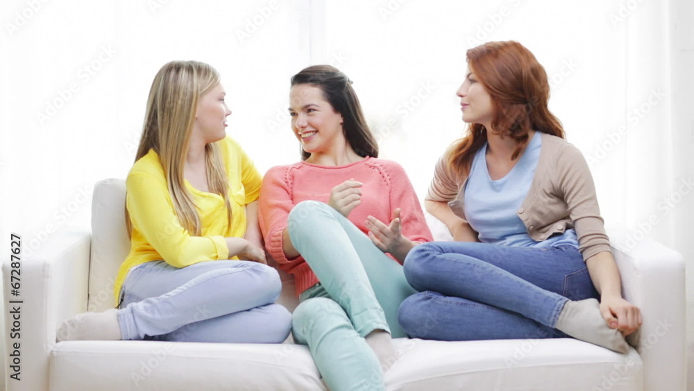 three smiling girlfriends having a talk at home three smiling girlfriends having a talk at home
